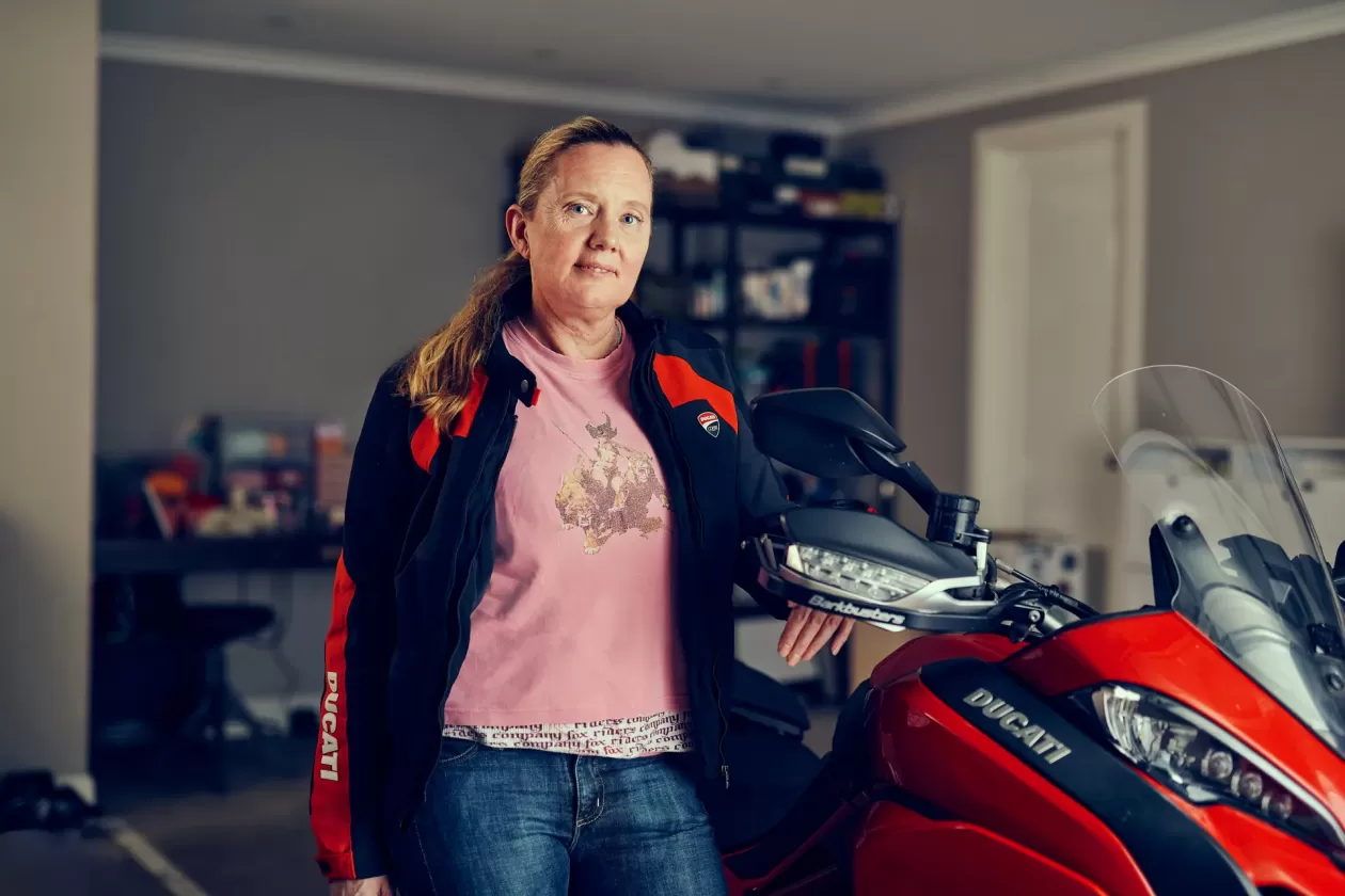 Woman standing next to motorcycle in a garage