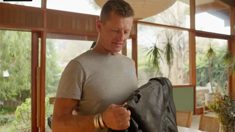 Image of Josh, a motorcycle rider, picking up his jacket in his home.